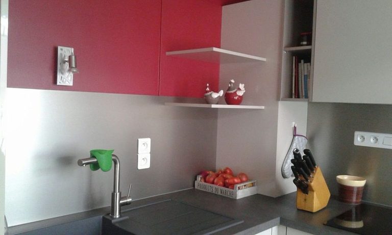 Mur rouge et étagères blanches au-dessus du plan de travail, niche ouverte dans les meubles hauts