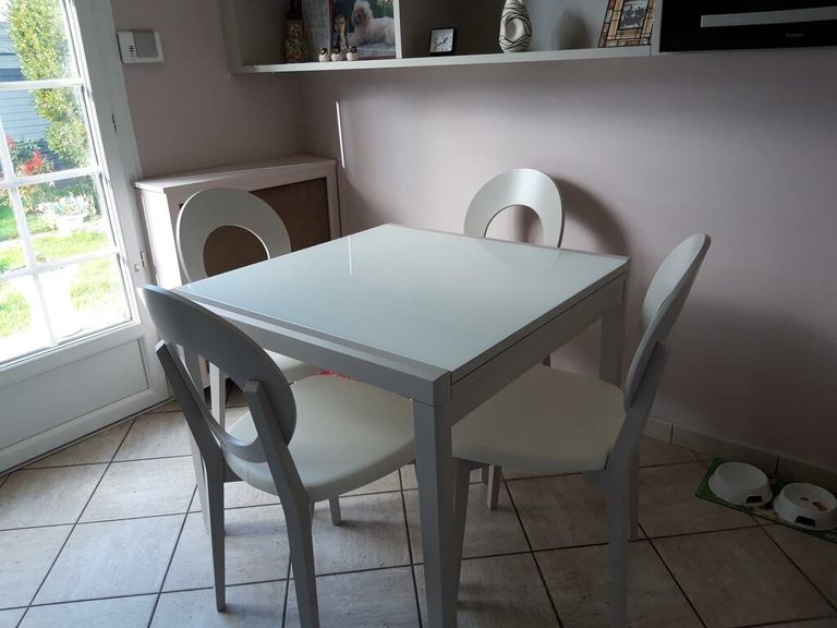 Coin repas attenant à la cuisine, murs rose poudré et mobilier blanc