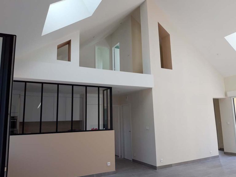 Séjour sous rampants rénové à Sainte-Luce-sur-Loire — murs clairs et verrière d'atelier