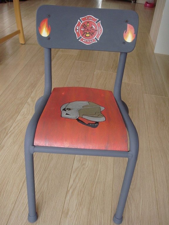 Chaise d'écolier relookée sur le thème des pompiers, assise rouge et casque peint