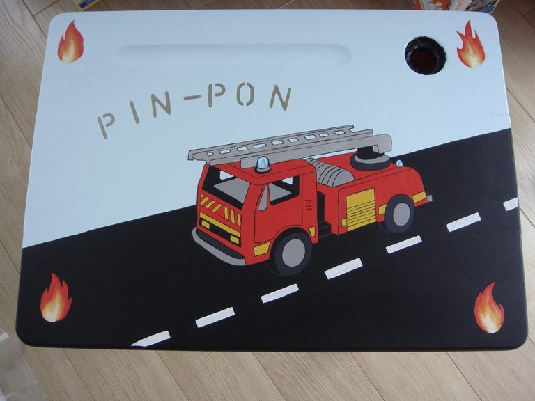 Plateau du bureau vu de dessus : camion de pompiers sur la route et lettrage PIN-PON