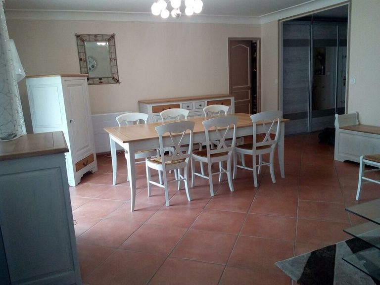 Chaises blanches et table à plateau bois, vue depuis l'entrée